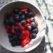 a bowl of berries and strawberries on a table