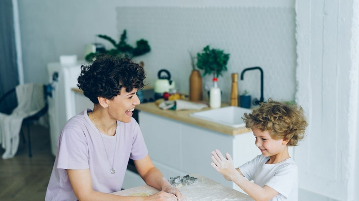 Mother and son having fun with flour cooking home-made cookies in kitchen